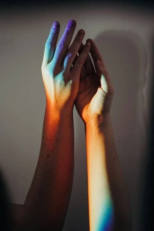 Twee handen belicht met wit, blauw en rood licht.